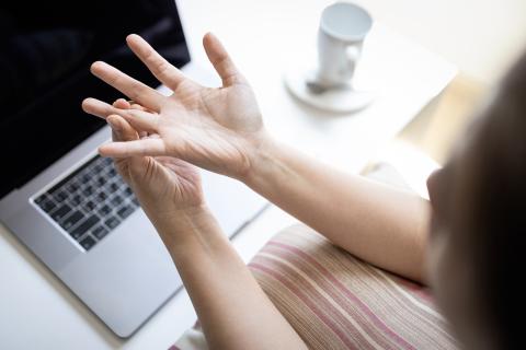 woman holding hand in pain by a computer